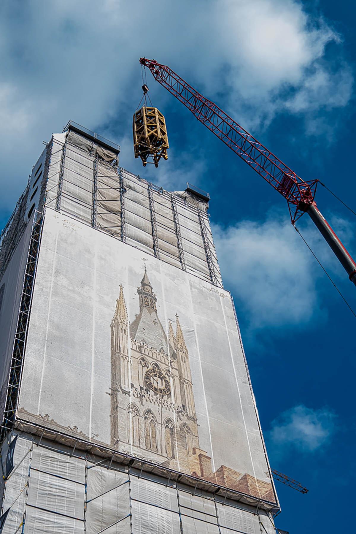 Met een grote kraan wordt de lantaarn op de toren gehesen.