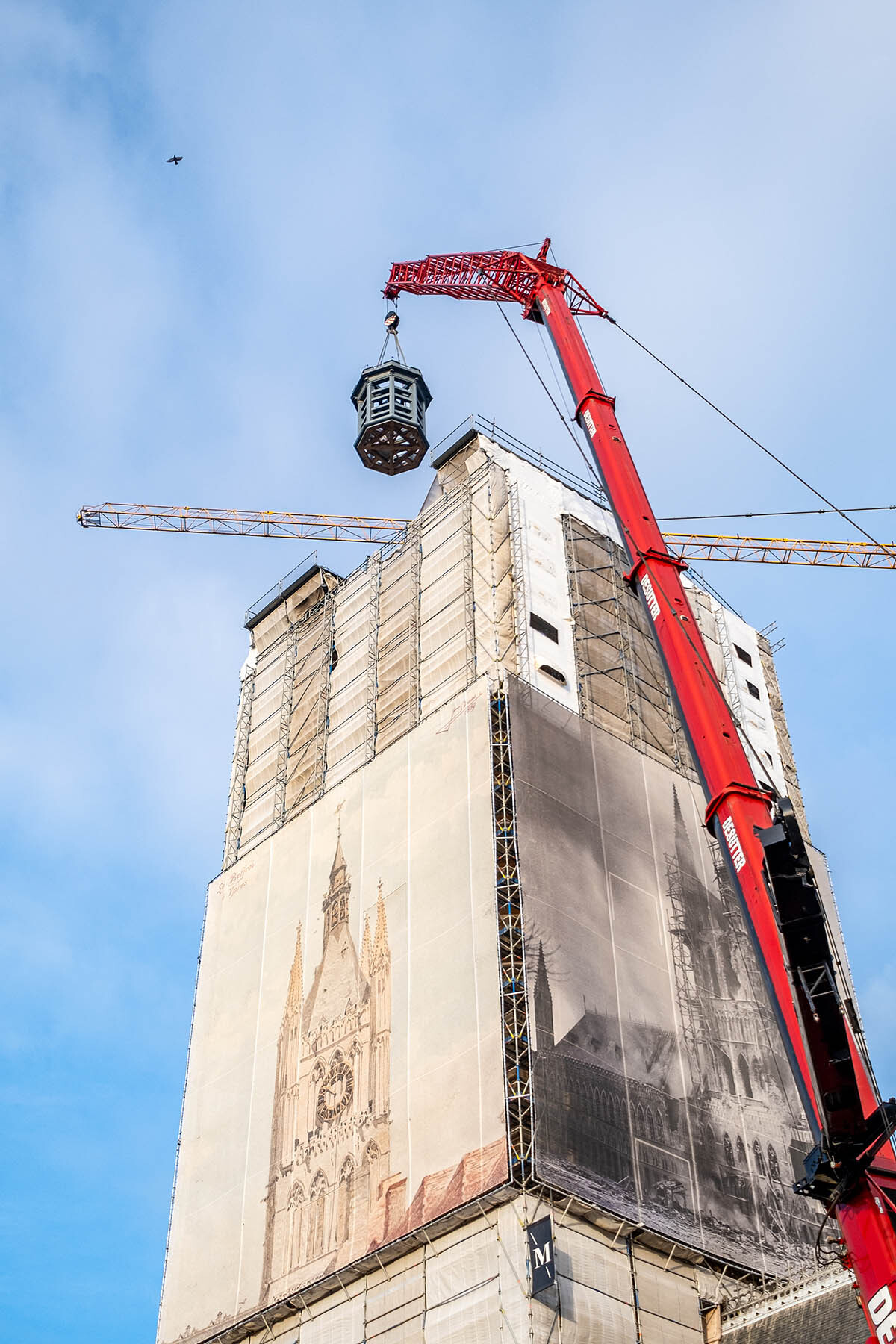 Met een grote kraan wordt de dakkapel op de toren gehesen.
